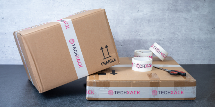 Mehrere Pakete liegen mit ein paar Rollen bedrucktem Klebeband auf einer Oberfläche