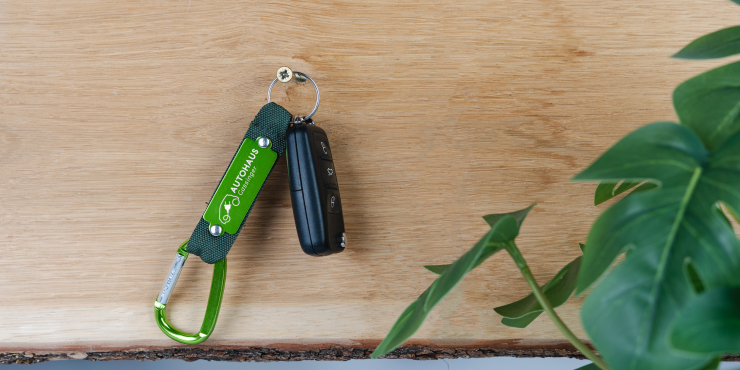 Ein individuell bedruckter Karabiner mit Schlüsselring hängt mit einem Autoschlüssel an einem Nagel