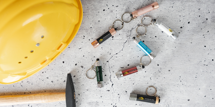 Mehrere Taschenlampen mit Schlüsselring liegen auf einer Baustelle