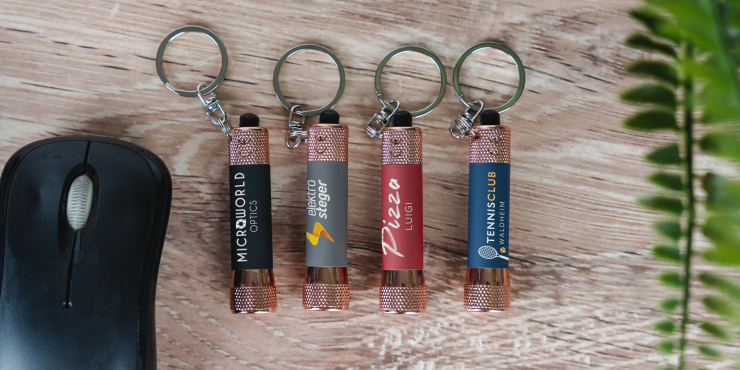 Mehrere bedruckte Taschenlampen liegen auf einem Schreibtisch neben einer Maus