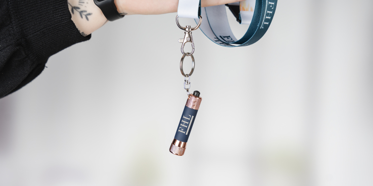 Eine Person hält ein Lanyard mit einer bedruckten Taschenlampe mit Schlüsselring in der Hand