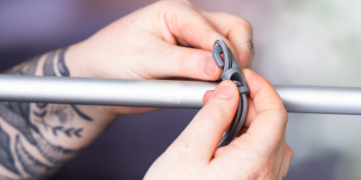 Person montiert Spannfix auf eine Metallstange