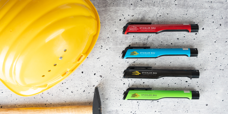 Mehrere Vega Taschenlampen neben einem Baustellenhelm und einem Hammer