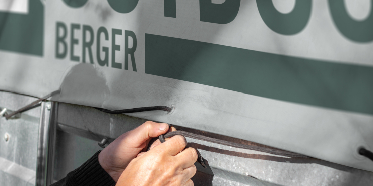 Eine Person fixiert die LKW-Plane