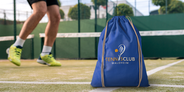 Individuell bedruckter Turnbeutel blau neben Tennisfeld