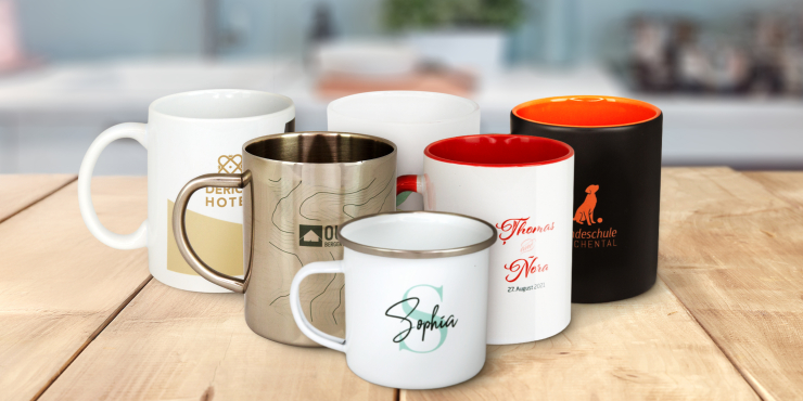 Mehrere Tassen aus unterschiedlichen Materialien stehen auf einem Holz