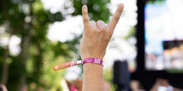 Eine Person hält ihren Arm mit einem bedruckten Festivalband die Luft