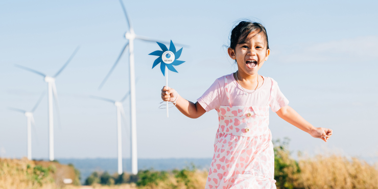 Ein Kind hält ein bedrucktes Windrad in der Hand und läuft in Richtung Kamera