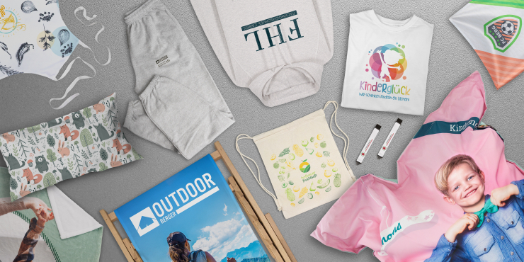 Diverse Werbeartikel mit Druck auf grauem Hintergrund