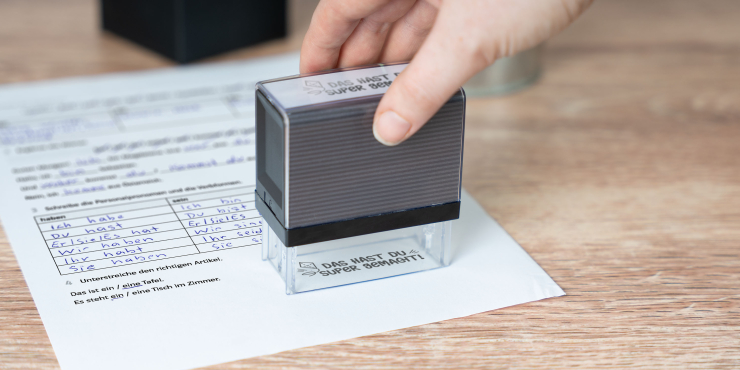 Person stempelt mit Colop Textstempel ein individuelles Motiv auf ein Blatt Papier