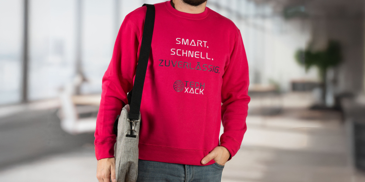 Mann geht ins Büro und trägt dunkelrosafarbenen Russell™-Sweater, der auf der vorderen Seite bedruckt ist