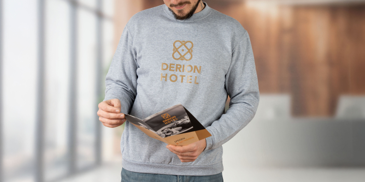 Mann liest Hotel-Broschüre in der Lobby und trägt einen grauen SOL&#039;S® Sweater mit Aufdruck auf der Brust