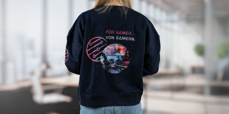 Weibliche Person steht im Büro und hat dunkelblauen Stanley/Stella-Hoodie mit hinterem Aufdruck an
