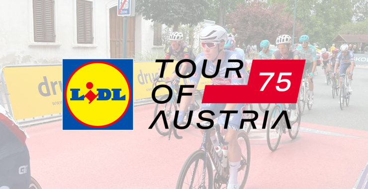 Tour of Austria Radfahrer neben druck.at Werbebannern und dem Logo in der Mitte
