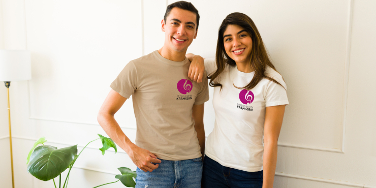 Pärchen mit Individuell bedruckten T-Shirts braun und weiß vor einer weißen Wand