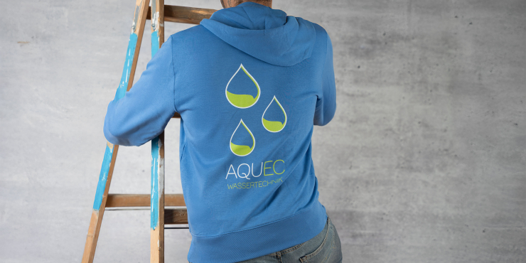 Heimwerker klettert die Leiter hinauf und trägt einen blauen Stanley/Stella-Zip-Hoodie, der am Rücken ein Logo aufgedruckt hat