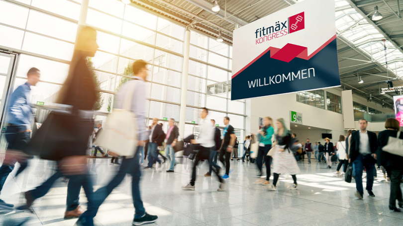 Viele Personen, die durch eine Messehalle gehen.