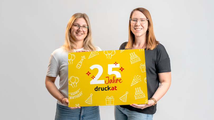 Zwei Frauen halten ein Schild in der Hand mit dem Aufdruck "25 Jahre druck.at"